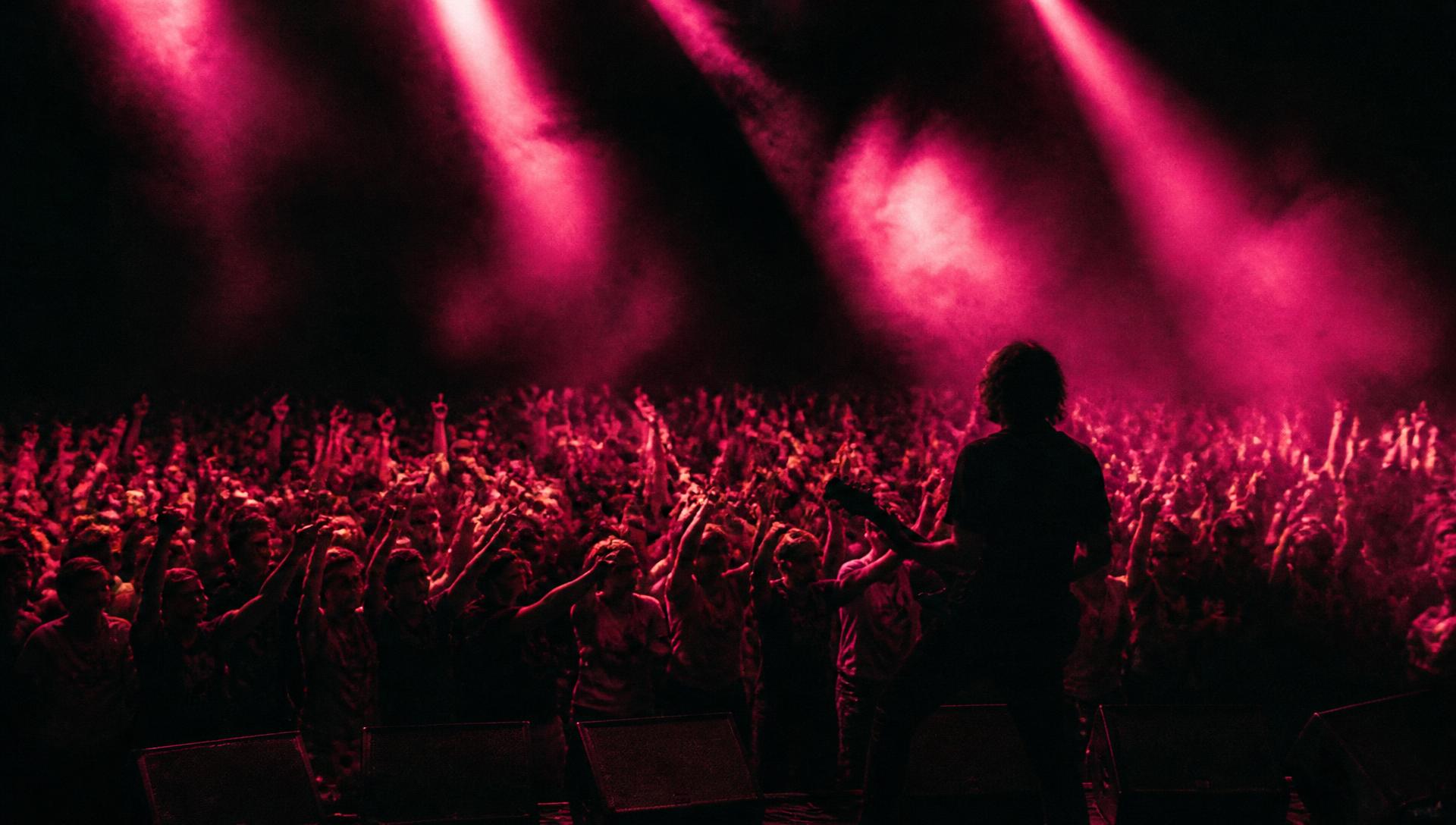 Plateia de um show lotado com luzes magenta